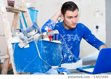 Male contractor working with papers and laptop Male contractor working with papers and laptop 53015495