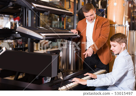 Happy boy and father deciding on synthesizer 53015497