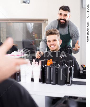 male hairdresser showing resulting haircut to client at hair salon 53015582