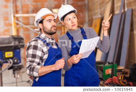 Workers man and woman discuss construction plan Workers man and woman discuss construction plan 53015945