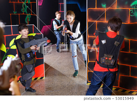 Group of happy teenagers with laser guns having fun on dark lasertag arena Group of happy teenagers with laser guns having fun on dark lasertag arena 53015949