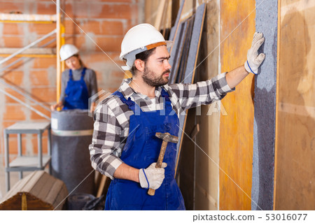Two professional builders sheathe walls with insulation Two professional builders sheathe walls with insulation 53016077
