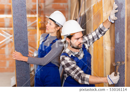 Two professional builders sheathe walls with insulation Two professional builders sheathe walls with insulation 53016114