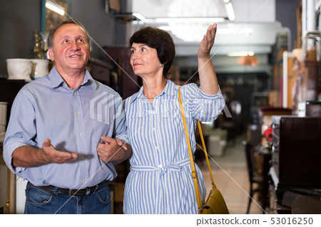 Smiling woman with her husband are buying furniture in antique store Smiling woman with her husband are buying furniture in antique store 53016250