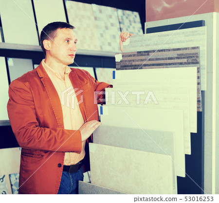 Customer carefully examines ceramic tiles Customer carefully examines ceramic tiles 53016253