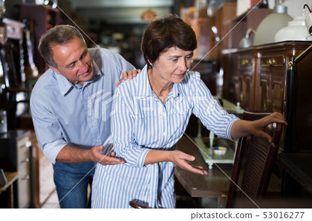 Mature man with his wife are buying armchair 53016277