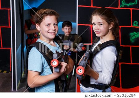 excited teen boy and girl aiming laser gun at other players 53016294