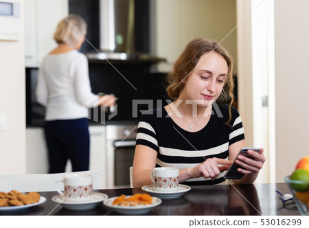 Woman with phone at kitchen Woman with phone at kitchen 53016299