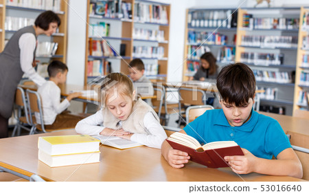 Girl and boy studying in school library Girl and boy studying in school library 53016640