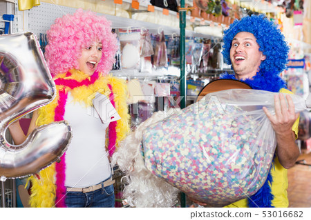 Laughing girl and guy are staying with large bagful of confetti 53016682