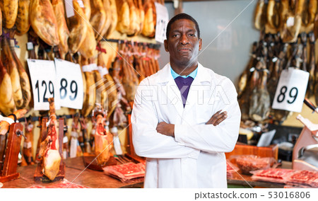 Butcher posing near ham counter 53016806