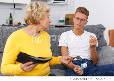 Mother giving some cash her son Mother giving some cash her son 53016922
