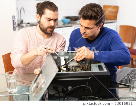 Two men repairing a desktop computer Two men repairing a desktop computer 53016951