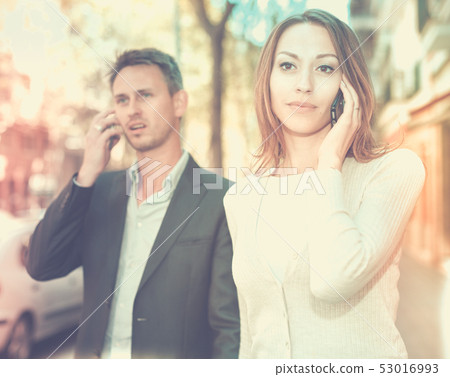 Girl and guy speaking on phones 53016993
