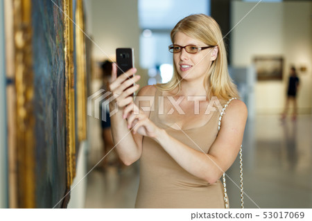 Woman looking at exposition and taking pictures 53017069