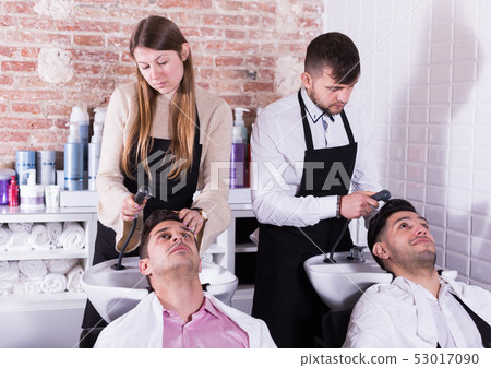 Men relaxing while hairdressers washing their hair Men relaxing while hairdressers washing their hair 53017090