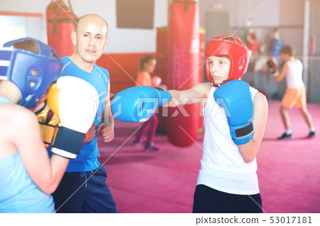 Two young boxer wearing gloves and helmet sparring 53017181