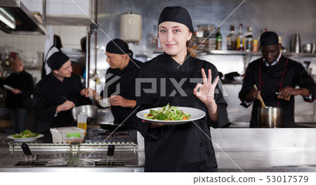 Confident female chef with a team of cooks in restaurant kitchen Confident female chef with a team of cooks in restaurant kitchen 53017579