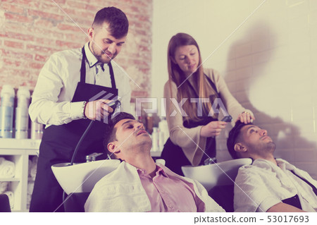Hairdressers washing hair of clients Hairdressers washing hair of clients 53017693