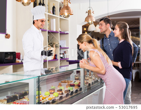 Positive pastry chef male is serving visitors Positive pastry chef male is serving visitors 53017695