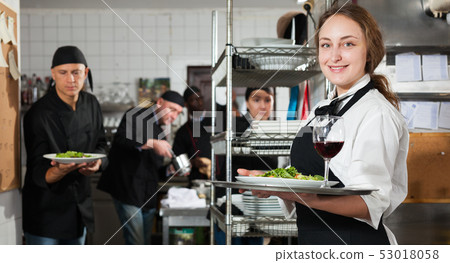 Waitress holding cooked meals at kitchen restaurant Waitress holding cooked meals at kitchen restaurant 53018058