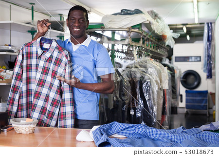 Worker of laundry showing clean clothing 53018673