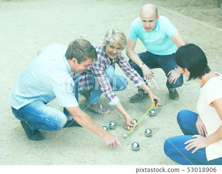 Cheerful males and females playing petanque Cheerful males and females playing petanque 53018906