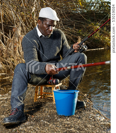 Fisherman sitting on wooden stool Fisherman sitting on wooden stool 53019084