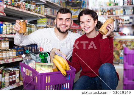 vigorous young family choosing purchasing canned food for week at supermarket 53019149