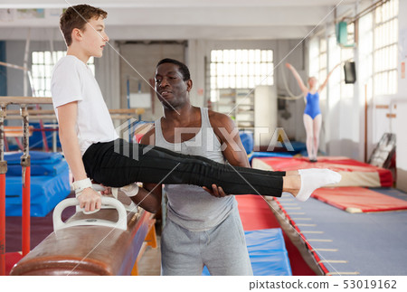 Fine African male coach helping teenage boy Fine African male coach helping teenage boy 53019162