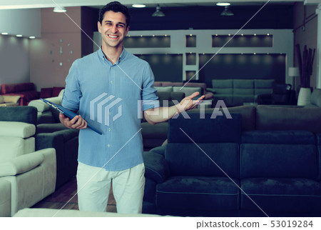 Seller male is demonstrating prices on sofas Seller male is demonstrating prices on sofas 53019284