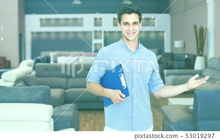 Salesman is demonstrating prices on sofas Salesman is demonstrating prices on sofas 53019297