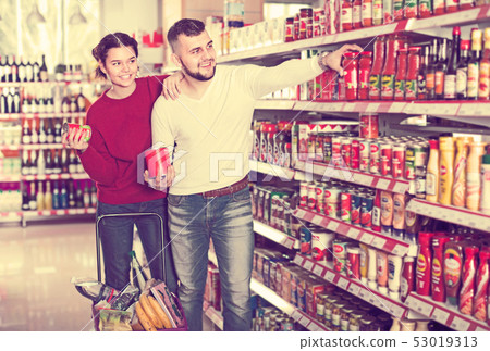 attentive couple choosing purchasing canned food for week at supermarket attentive couple choosing purchasing canned food for week at supermarket 53019313