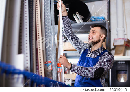 Young man worker examining plastic corners for tiles and floors Young man worker examining plastic corners for tiles and floors 53019443