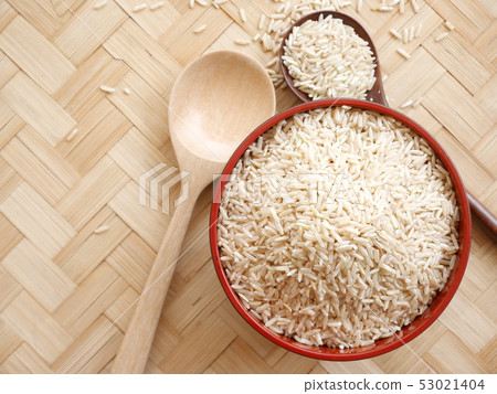 organic raw rice on brown wood spoon and in bowl organic raw rice on brown wood spoon and in bowl 53021404