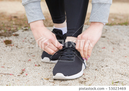Woman tying shoelaces Woman tying shoelaces 53023469