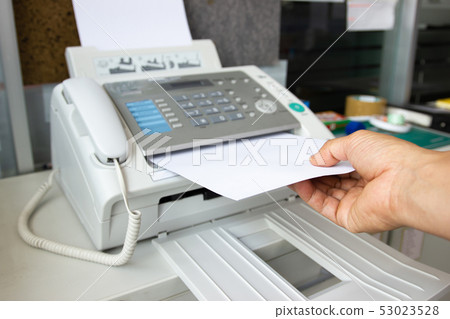 Hand man are using a fax machine in the office 53023528