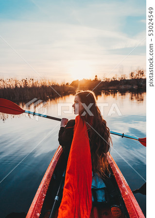 Back view of happy cute girl holding paddle in a kayak on the river 53024549
