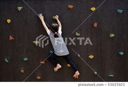 Girl playing on a climbing wall 53025921