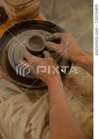 Accurate talented man with strong hands molding wet clay Accurate talented man with strong hands molding wet clay 53026469