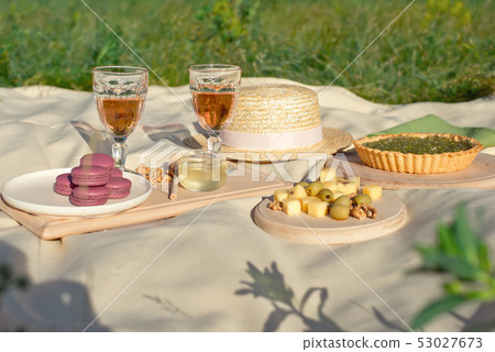 Picnic basket with fruit and macaroon bakery transparent glasses of drink on a beige fabric in the 53027673