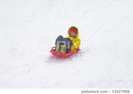 Little Japanese girl is sliding down the snow sled 53027906