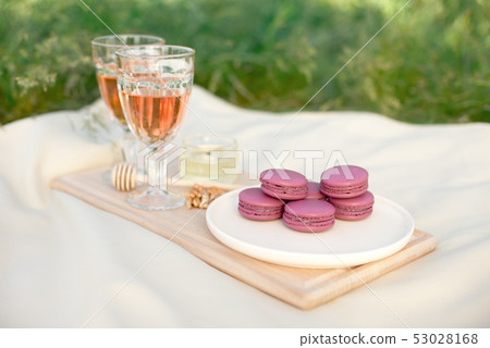 Light pink and fuchsia pink french macaroons or macaroons with glass goblets of pink wine in a round 53028168