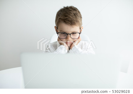 Cute little boy using laptop while doing homework against white background Cute little boy using laptop while doing homework against white background 53029028