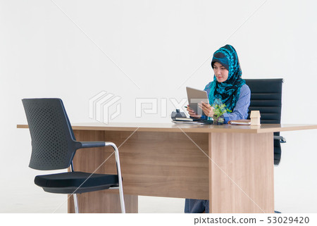 Muslim woman is using digital tablet on office Muslim woman is using digital tablet on office 53029420