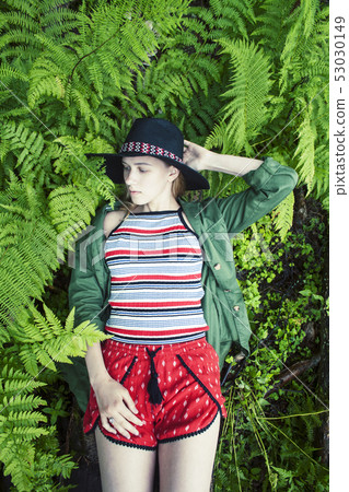Pretty young blond girl hipster in hat among fern, vacation in green forest, lifestyle people 53030149