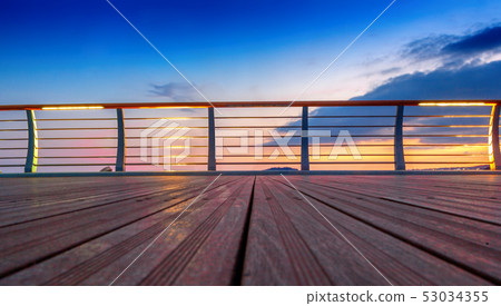Wooden platform and railing on the background of a bright sunset, abstract background 53034355