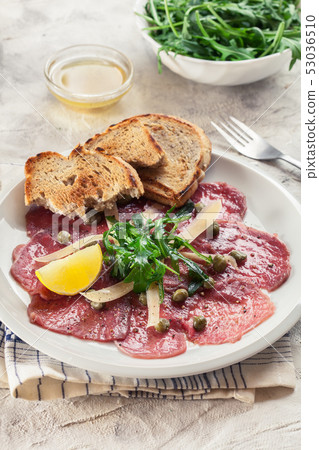 Beef carpaccio with arugula and parmesan Beef carpaccio with arugula and parmesan 53036510