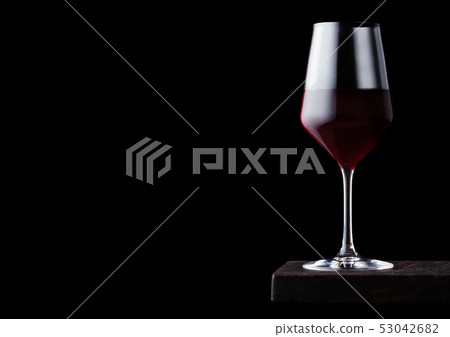 Glass of red wine on wooden board on black 53042682
