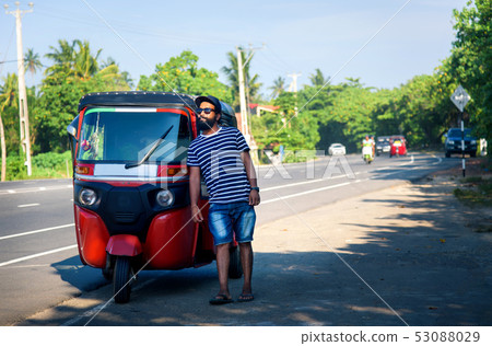 Cheerful man standing by the tuk tuk taxi Cheerful man standing by the tuk tuk taxi 53088029